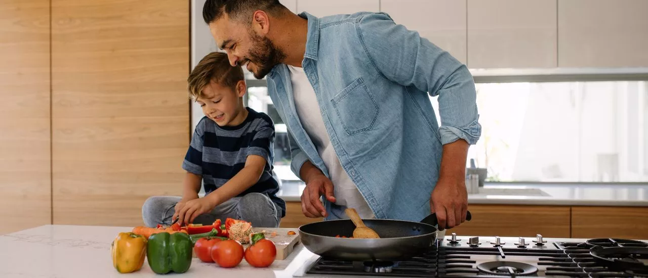 Concetto di buoni pasto e salute: padre e figlio cucinano insieme
