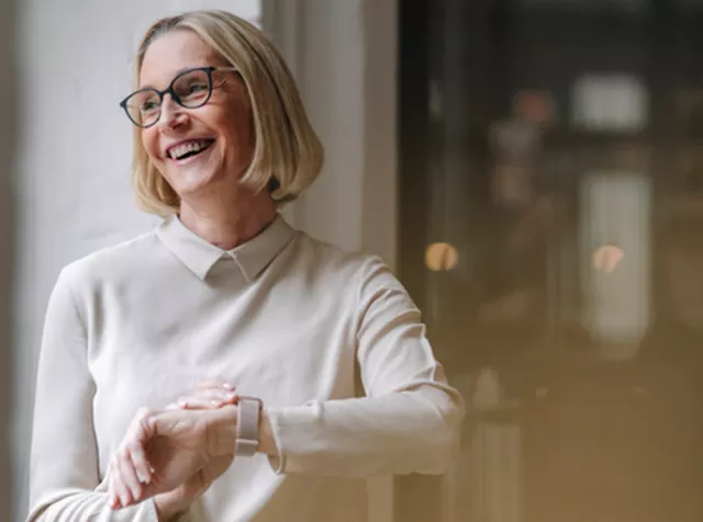 un ragazzo sorridendo guarda lo smartphone simboleggiando la facilità con cui gli utilizzatori trovano i locali convenzionati sull’App