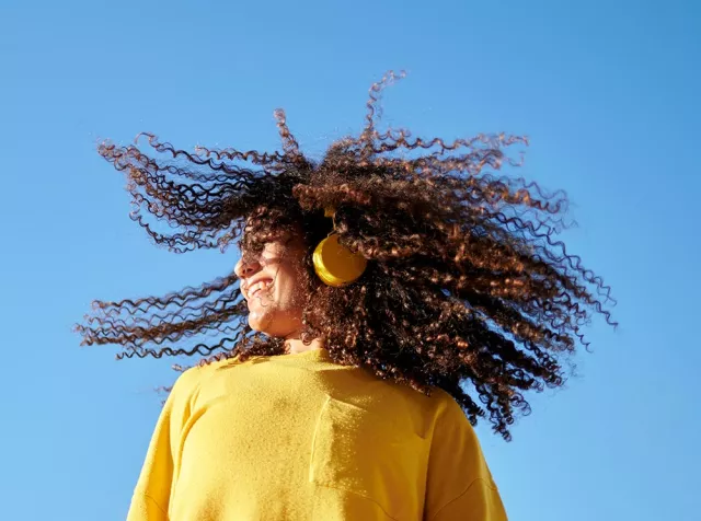 Immagine di una ragazza che sorride ascoltando la musica. Noi di Pluxee ci prendiamo cura dei nostri clienti.