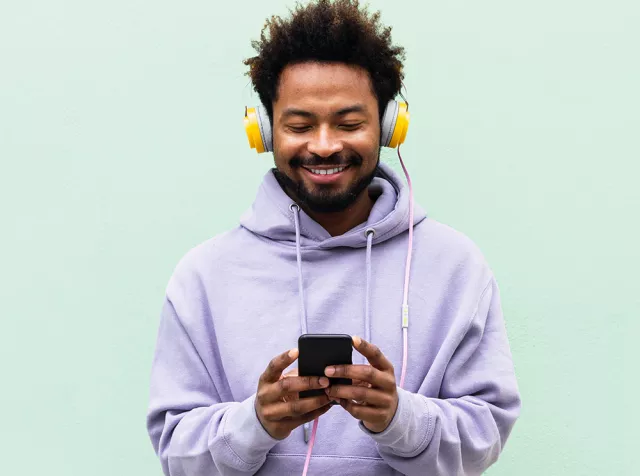 Immagine di un ragazzo che sorride guardando il telefono. I Buoni Acquisto Pluxee aprono un mondo di opportunità per lo shopping.