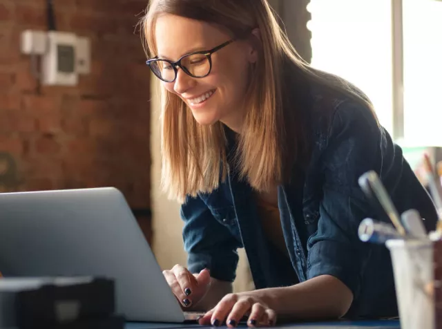 immagine di una ragazza al computer che sorride. Usare i Buoni Acquisto Pluxee è davvero semplice, veloce e comodo.