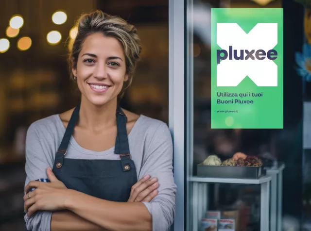 Immagine di un esercente che sorride davanti al suo negozio. Rappresenta i vantaggi e le opportunità di business che le soluzioni Pluxee apportano ai nostri partner commerciali.