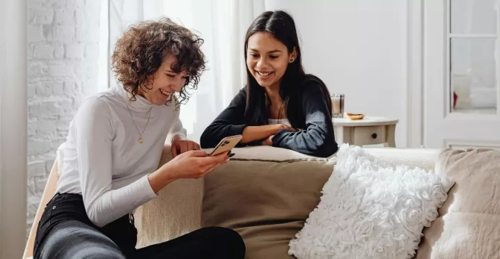 due amiche che guardano insieme lo schermo del cellulare, simbolo di benessere