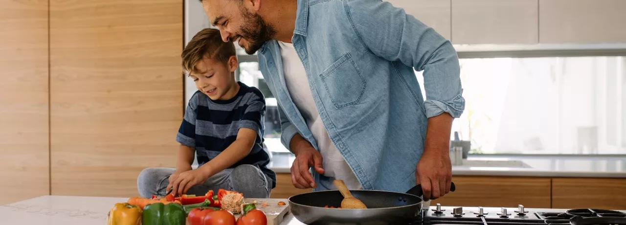 Concetto di buoni pasto e salute: padre e figlio cucinano insieme
