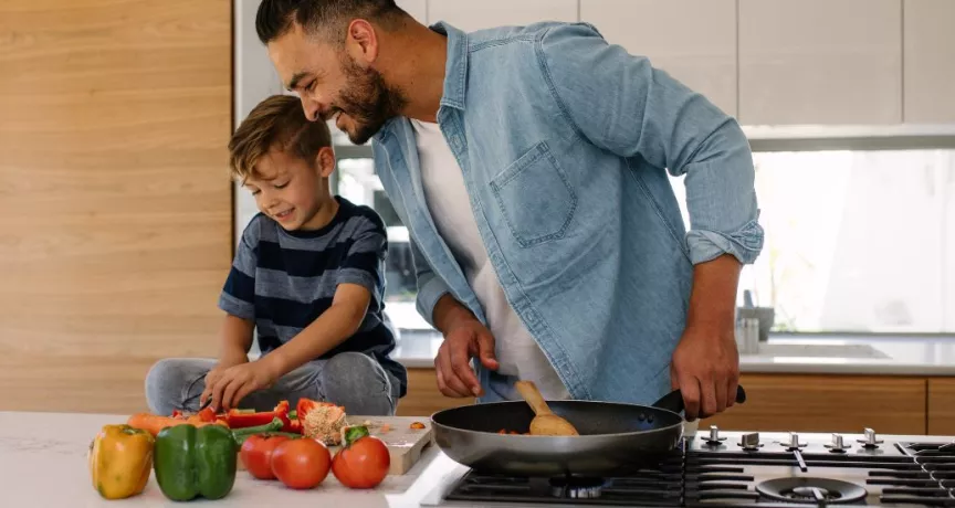 Concetto di buoni pasto e salute: padre e figlio cucinano insieme