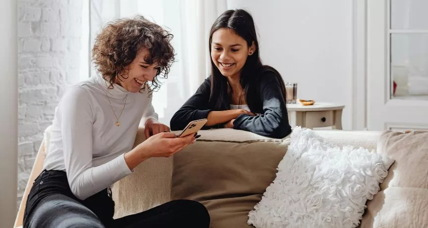 due amiche che guardano insieme lo schermo del cellulare, simbolo di benessere