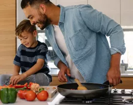 Concetto di buoni pasto e salute: padre e figlio cucinano insieme