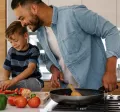 Concetto di buoni pasto e salute: padre e figlio cucinano insieme