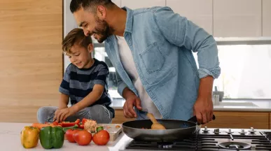 Concetto di buoni pasto e salute: padre e figlio cucinano insieme