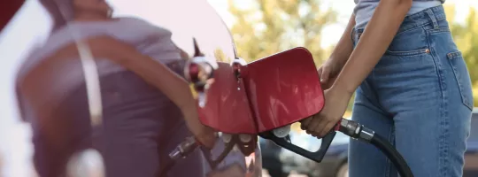 Una mano al volante che guida una macchina su una grande strada rappresenta il Buono Acquisto Benzina Pluxee 